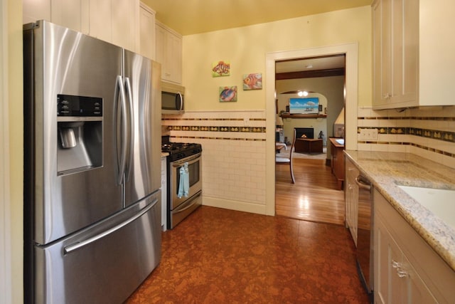 9 Harwood Pl, Bloomington, IL 61701 - kitchen featuring appliances with stainless steel finishes, tile walls, light stone countertops, dark flooring, and a wainscoted wall