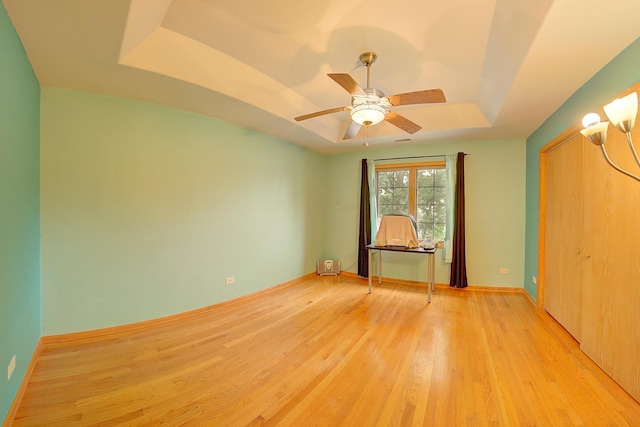4914 W 82nd St, Burbank, IL 60459 - unfurnished bedroom featuring a tray ceiling, light wood finished floors, and a ceiling fan