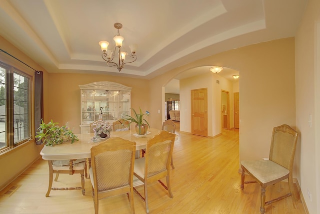 4914 W 82nd St, Burbank, IL 60459 - dining space featuring a tray ceiling, arched walkways, a chandelier, and light wood-type flooring