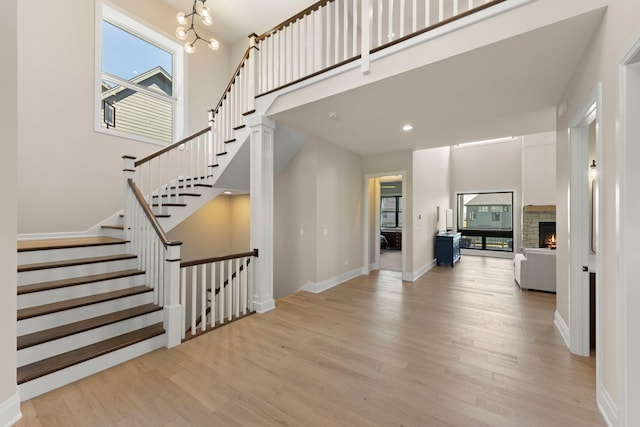 4216 Carpenter Rd, Naperville, IL 60564 - stairway featuring wood finished floors, healthy amount of natural light, a high ceiling, a chandelier, and a stone fireplace