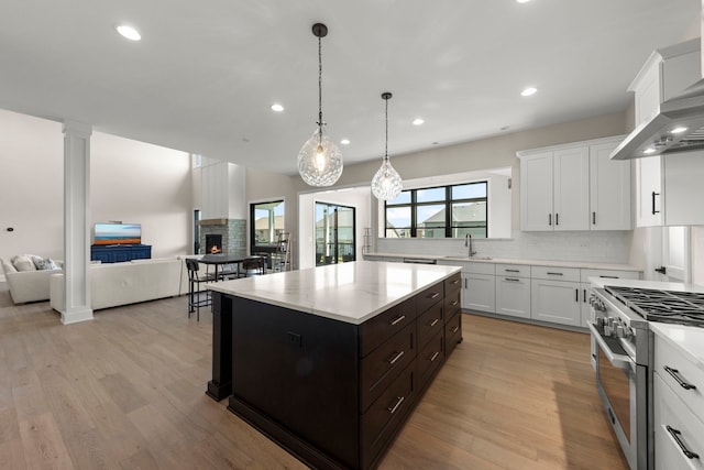 4216 Carpenter Rd, Naperville, IL 60564 - kitchen featuring high end range, wall chimney exhaust hood, open floor plan, tasteful backsplash, and white cabinets