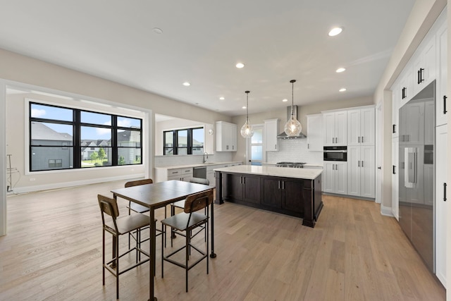 4216 Carpenter Rd, Naperville, IL 60564 - kitchen with wall chimney exhaust hood, light countertops, light wood finished floors, a center island, and white cabinetry