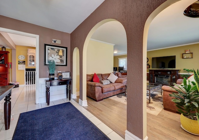 1213 Rose Ct, Bartlett, IL 60103 - living area with arched walkways, a glass covered fireplace, light tile patterned floors, and crown molding