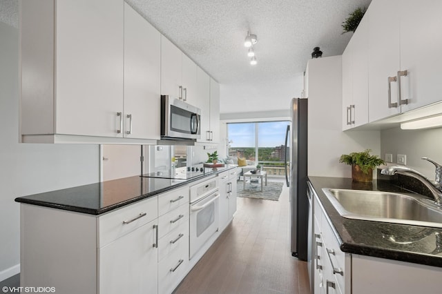 800 Elgin Rd Unit 1406, Evanston, IL 60201 - kitchen with appliances with stainless steel finishes, a textured ceiling, white cabinets, wood finished floors, and rail lighting