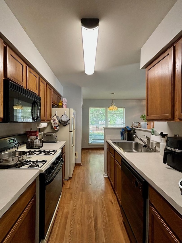 14155 S Hemingway Cir, Plainfield, IL 60544 - kitchen featuring black appliances, light countertops, light wood finished floors, brown cabinets, and a peninsula