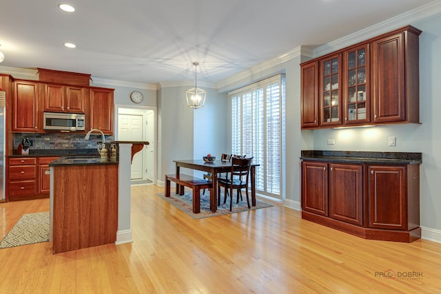 870 Symphony St, Lake Forest, IL 60045 - kitchen featuring stainless steel microwave, light wood-style flooring, glass insert cabinets, decorative backsplash, and hanging light fixtures
