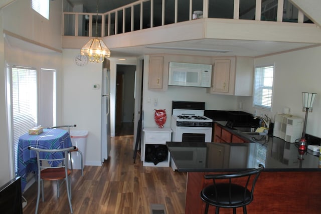 183 Fossil Cove Ct, Wilmington, IL 60481 - kitchen with white appliances, dark wood-type flooring, dark countertops, a chandelier, and a breakfast bar area