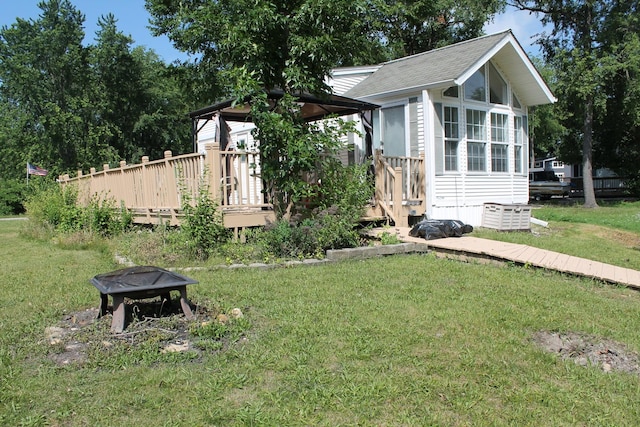 183 Fossil Cove Ct, Wilmington, IL 60481 - view of property exterior with a wooden deck, a yard, an outdoor fire pit, a sunroom, and a shingled roof