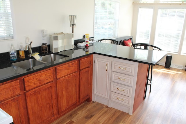 183 Fossil Cove Ct, Wilmington, IL 60481 - kitchen featuring light wood-style flooring, a peninsula, a breakfast bar, brown cabinetry, and dark stone counters