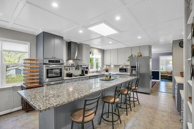 201 E Sherwin Dr, Urbana, IL 61802 - kitchen featuring stainless steel appliances, wall chimney exhaust hood, a breakfast bar area, gray cabinetry, and light tile patterned floors