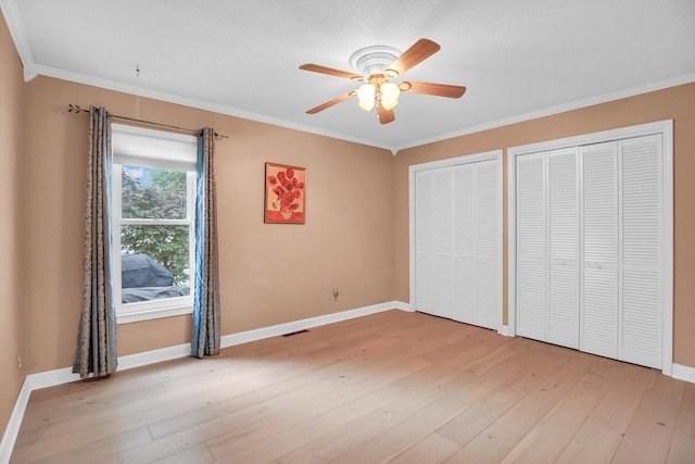 201 E Sherwin Dr, Urbana, IL 61802 - unfurnished bedroom with multiple closets, ornamental molding, light wood-type flooring, and ceiling fan
