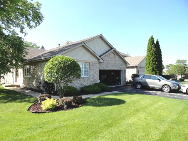 view of front of home with a garage, stone siding, and a front lawn