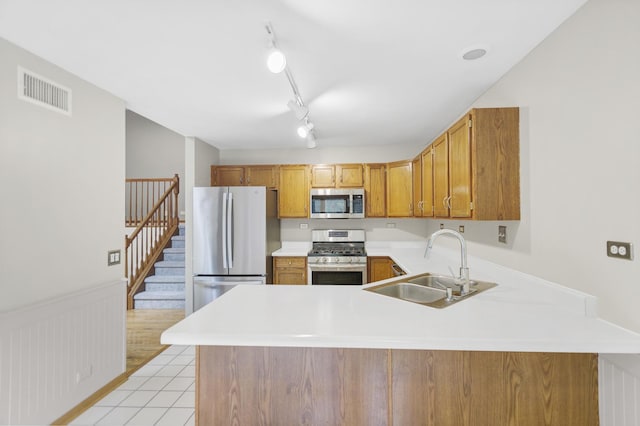 924 Millcreek Cir, Elgin, IL 60123 - kitchen with stainless steel appliances, light countertops, a peninsula, brown cabinetry, and a wainscoted wall
