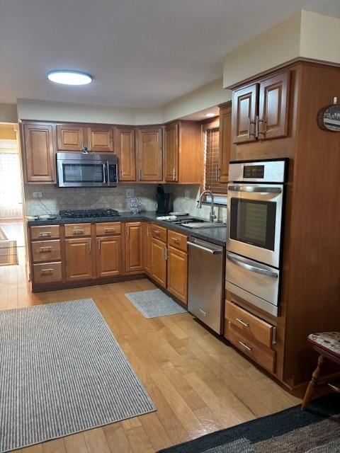 5131 S Latrobe Ave, Chicago, IL 60638 - kitchen featuring stainless steel appliances, a warming drawer, light wood-style floors, tasteful backsplash, and dark countertops