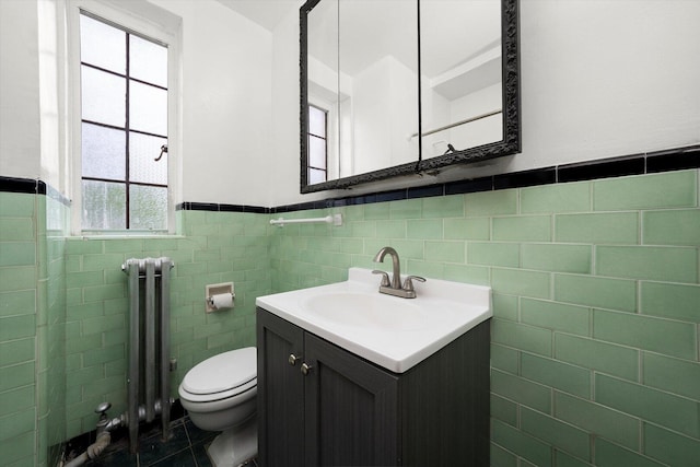 3017 E 78th St Unit 4B, Chicago, IL 60649 - bathroom featuring radiator heating unit, tile walls, vanity, a wainscoted wall, and tile patterned flooring