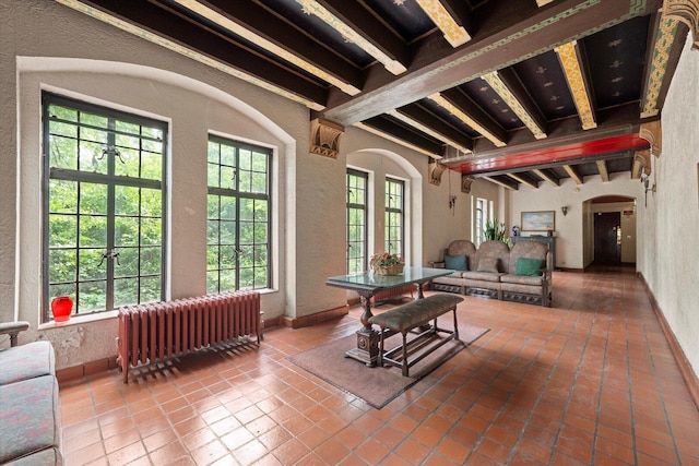 3017 E 78th St Unit 4B, Chicago, IL 60649 - living area with radiator heating unit, beamed ceiling, a textured wall, arched walkways, and tile patterned floors