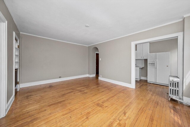 3017 E 78th St Unit 4B, Chicago, IL 60649 - unfurnished living room featuring radiator heating unit, arched walkways, light wood-style flooring, and ornamental molding
