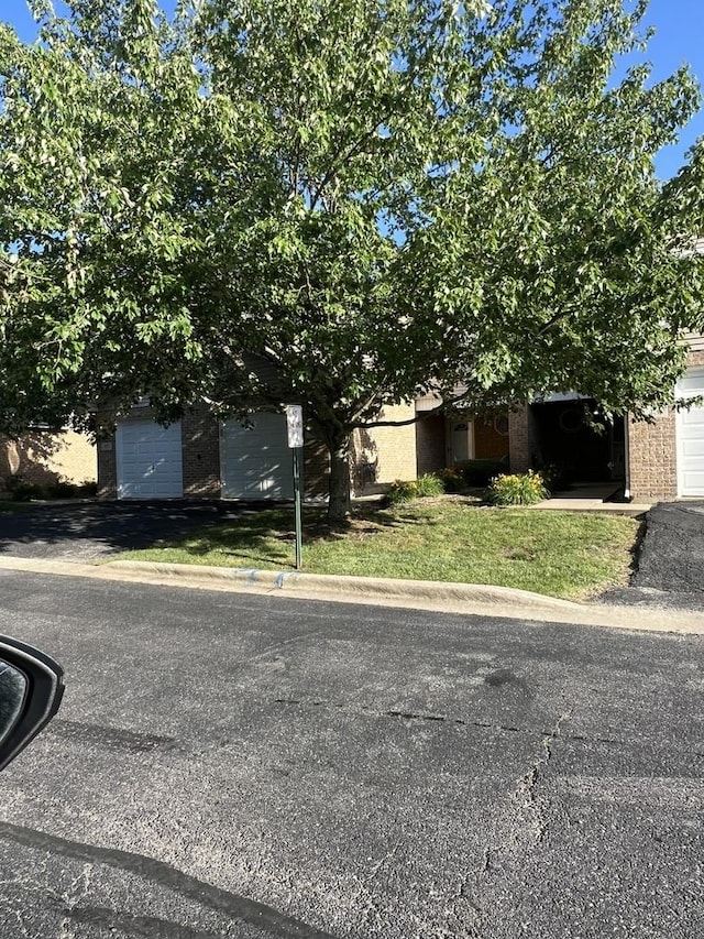 view of property hidden behind natural elements with brick siding