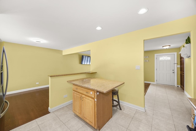 9070 Shady Ln, Hickory Hills, IL 60457 - kitchen featuring a breakfast bar area, light tile patterned flooring, a center island, light stone countertops, and recessed lighting