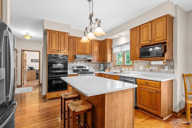 10660 Great Egret Dr, Orland Park, IL 60467 - kitchen featuring black appliances, under cabinet range hood, light countertops, and brown cabinets