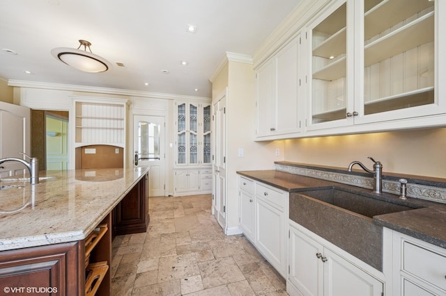1550 N State Pkwy Unit 801, Chicago, IL 60610 - kitchen featuring crown molding, stone tile floors, dark stone countertops, white cabinets, and glass insert cabinets