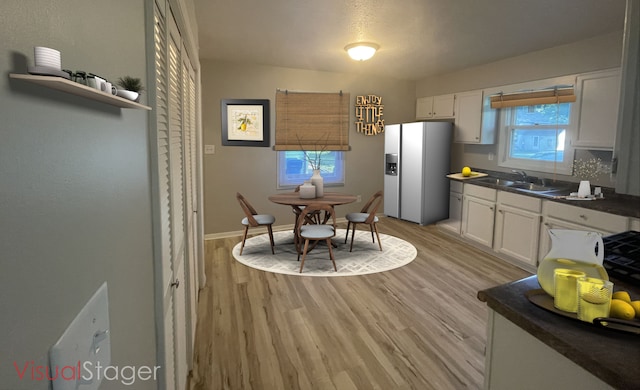 522 N 3rd Ave, Chenoa, IL 61726 - kitchen with white fridge with ice dispenser, dark countertops, white cabinets, and light wood finished floors