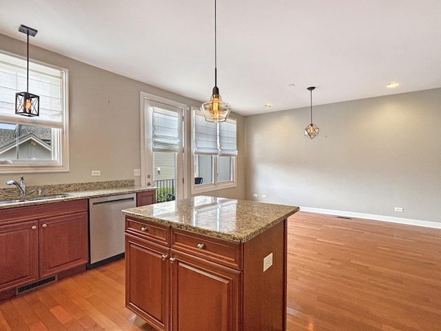 15 Busse Hwy, Park Ridge, IL 60068 - kitchen with stainless steel dishwasher, light wood-type flooring, brown cabinets, light stone countertops, and a kitchen island