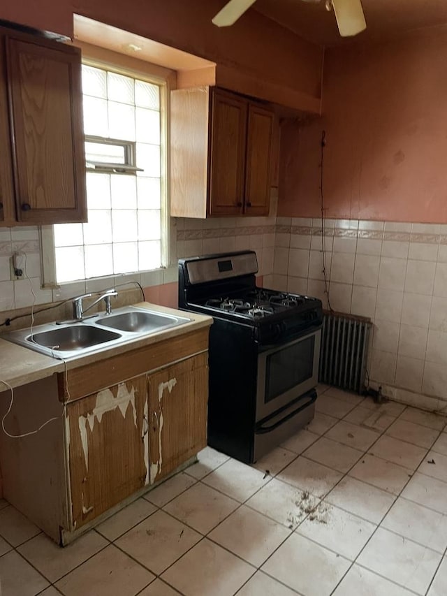 7240 S Lafayette Ave, Chicago, IL 60621 - kitchen with stainless steel gas stove, radiator, brown cabinets, light countertops, and light tile patterned floors
