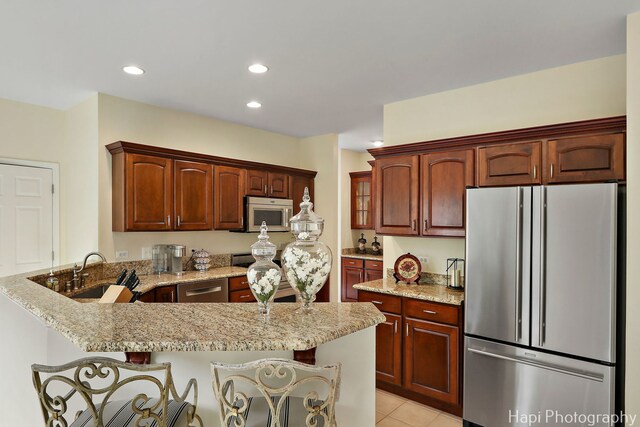 4 Shadow Creek Ct, Lake In The Hills, IL 60156 - kitchen featuring appliances with stainless steel finishes, a peninsula, light stone countertops, a kitchen bar, and light tile patterned floors