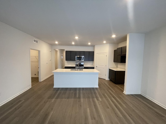 2522 Redwood Trl, Wonder Lake, IL 60097 - kitchen featuring stainless steel microwave, a kitchen island with sink, dark wood-type flooring, light countertops, and recessed lighting