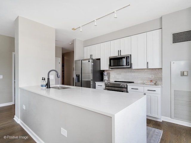 421 W Huron St Unit 1005, Chicago, IL 60654 - kitchen featuring stainless steel appliances, a peninsula, dark wood-style flooring, track lighting, and backsplash