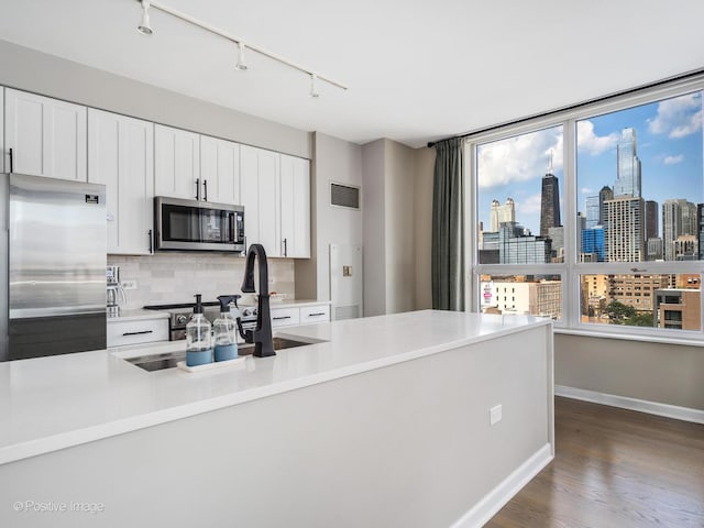 421 W Huron St Unit 1005, Chicago, IL 60654 - kitchen featuring stainless steel appliances, dark wood-style floors, backsplash, light countertops, and white cabinets