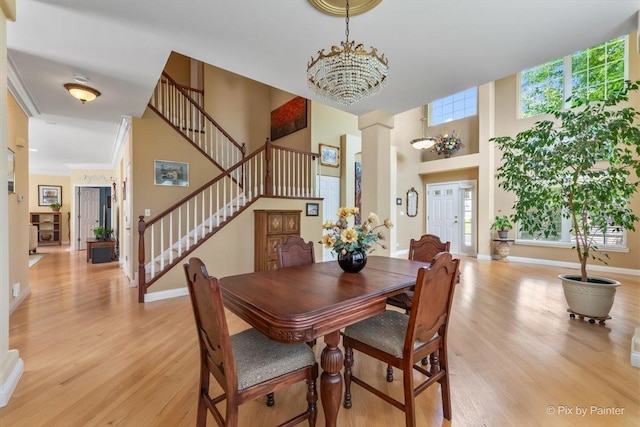 2636 Bainbridge Blvd, West Chicago, IL 60185 - dining space with stairs, light wood-style flooring, a towering ceiling, ornate columns, and a chandelier