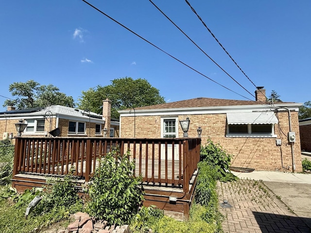 9424 Lorel Ave, Skokie, IL 60077 - rear view of house with brick siding, a wooden deck, and a chimney