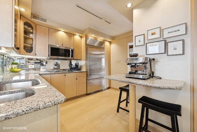 1440 N State Pkwy Unit 21C, Chicago, IL 60610 - kitchen with stainless steel appliances, light brown cabinets, light wood-type flooring, light stone counters, and glass insert cabinets