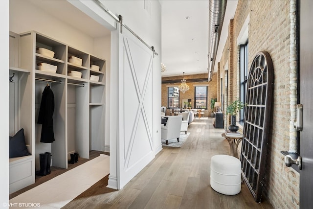 401 N Aberdeen St Unit 4S, Chicago, IL 60642 - mudroom featuring a barn door, hardwood / wood-style floors, a chandelier, brick wall, and a towering ceiling