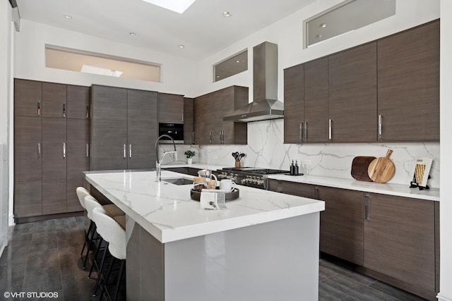 401 N Aberdeen St Unit 4S, Chicago, IL 60642 - kitchen with wall chimney range hood, a kitchen bar, dark brown cabinetry, decorative backsplash, and a center island with sink
