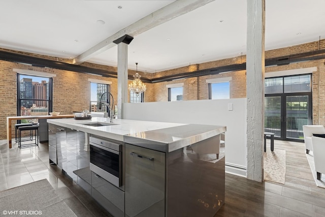 401 N Aberdeen St Unit 4S, Chicago, IL 60642 - kitchen with modern cabinets, a towering ceiling, a chandelier, stainless steel microwave, and brick wall