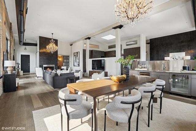 401 N Aberdeen St Unit 4S, Chicago, IL 60642 - dining space with beverage cooler, a chandelier, light wood-type flooring, and a large fireplace