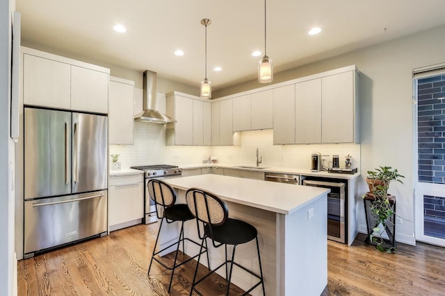 1800 N California Ave Unit 1E, Chicago, IL 60647 - kitchen featuring appliances with stainless steel finishes, wall chimney exhaust hood, wood finished floors, a kitchen breakfast bar, and a center island