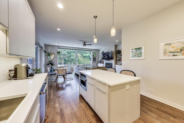 1800 N California Ave Unit 1E, Chicago, IL 60647 - kitchen with dark wood-style floors, a ceiling fan, tasteful backsplash, light countertops, and pendant lighting