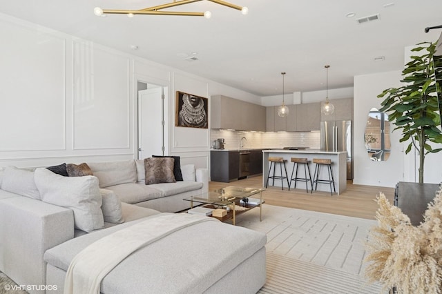 2405 W Iowa St Unit 206, Chicago, IL 60622 - living room featuring light wood-style flooring, a decorative wall, and a chandelier