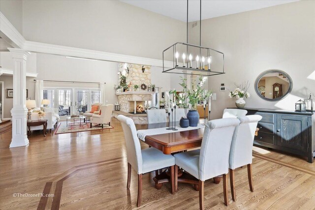 1417 Sherwood Ln, Geneva, IL 60134 - dining area featuring ornate columns, a lit fireplace, light wood-type flooring, and a high ceiling