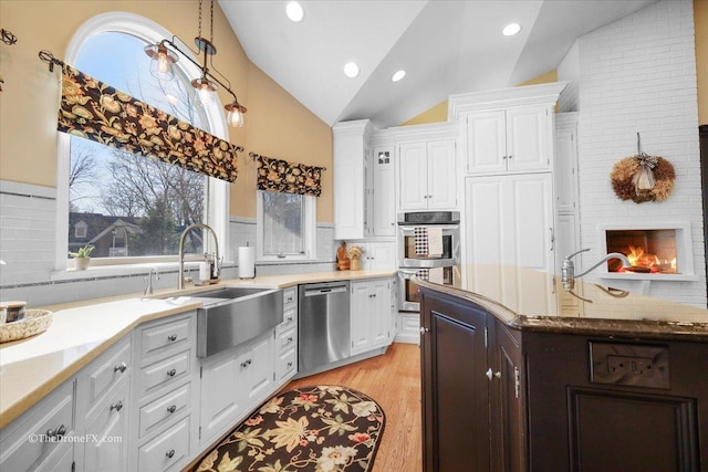 1417 Sherwood Ln, Geneva, IL 60134 - kitchen with appliances with stainless steel finishes, vaulted ceiling, white cabinets, light wood finished floors, and a fireplace
