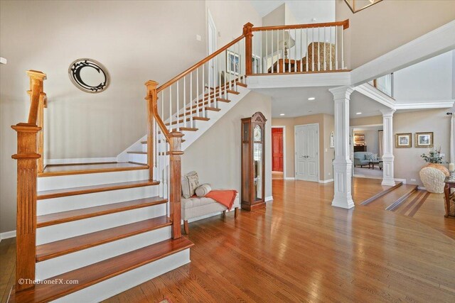 1417 Sherwood Ln, Geneva, IL 60134 - staircase featuring ornate columns, a high ceiling, wood finished floors, and recessed lighting