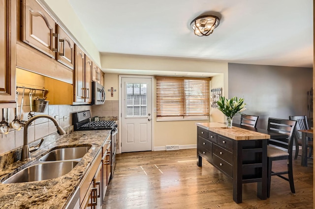 905 Harrison Ln, Hoffman Estates, IL 60192 - kitchen with stainless steel appliances, wood finished floors, decorative backsplash, light stone counters, and brown cabinetry