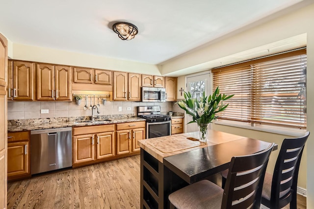 905 Harrison Ln, Hoffman Estates, IL 60192 - kitchen with stainless steel appliances, light wood finished floors, tasteful backsplash, light stone countertops, and brown cabinetry