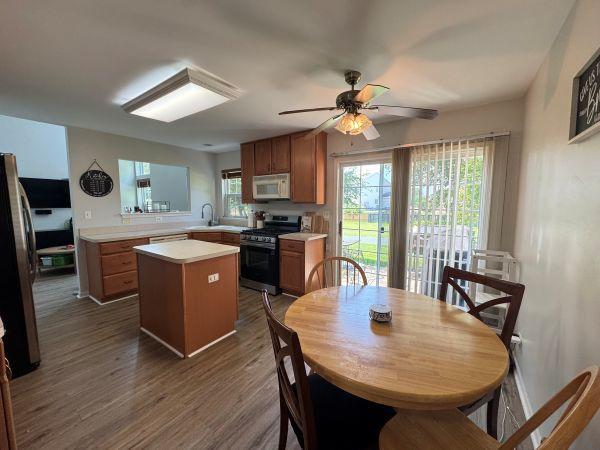 475 Lancaster Dr, Pingree Grove, IL 60140 - kitchen featuring range with gas stovetop, white microwave, light countertops, a kitchen island, and a ceiling fan