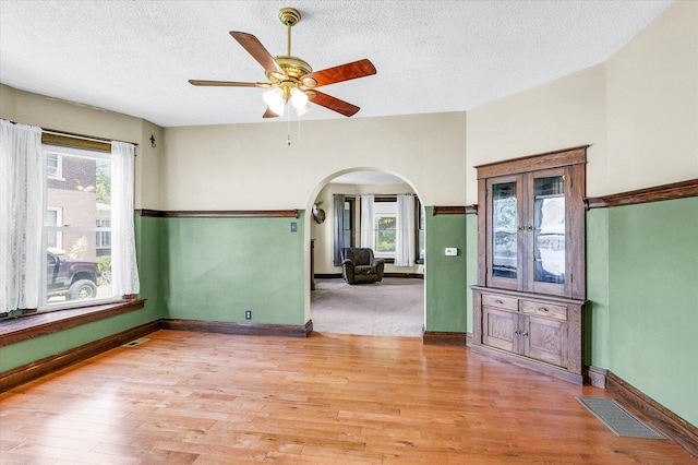 301 N Main St, Fithian, IL 61844 - empty room featuring arched walkways, light wood-style floors, a textured ceiling, and ceiling fan