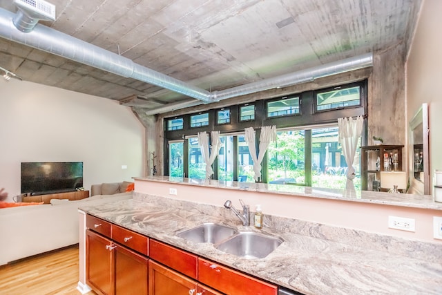 1070 W 15th St Unit 105, Chicago, IL 60608 - kitchen featuring light wood-type flooring, light stone counters, brown cabinetry, and open floor plan